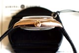 Side view of vintage rose gold Swiss watch with bubbleback case and black leather strap