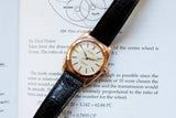 Vintage rose gold bubble back watch with black leather strap on open book