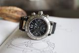 Stainless steel chronograph watch with black dial and subdials on a sketchbook background