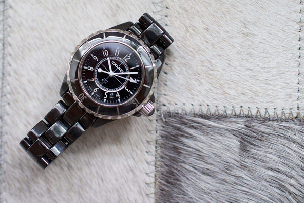 Black ceramic women's luxury watch with round case on a light stitched fur surface