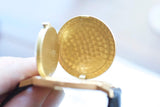 Close-up of an open gold luxury watch case showing a textured interior.