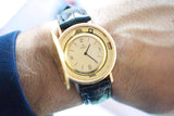 Close-up of a vintage gold Ebel luxury watch with a black leather strap on a wrist.
