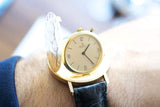 Close-up of a vintage gold Ebel pocket watch with an open cover on a wrist.