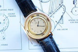 Vintage gold Ebel watch with a black leather strap resting on a technical blueprint.