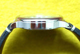 Side view of a luxury Swiss-made watch with a polished silver case and black leather strap.