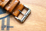 Close-up of a tan leather luxury watch strap with a silver E&C buckle