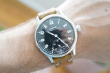 Close-up of a vintage Eberhard & Co. luxury watch with a brown leather strap on a wrist.