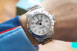 Rolex Explorer II luxury wristwatch with white dial and steel bezel on a person's wrist