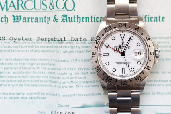 Rolex Oyster Perpetual Date Explorer II luxury watch resting on its original warranty certificate