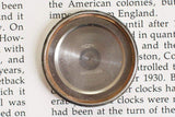 Stainless steel watch case back on text background for luxury chronograph watch