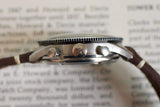 Close-up side view of vintage chronograph watch with a brown leather strap