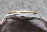 Side profile view of a luxury stainless steel watch with a gold fluted bezel