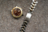 Rolex GMT-Master II watch with brown bezel and two-tone steel and gold bracelet on grey fabric