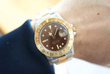Close-up of a Rolex GMT-Master II luxury watch with a gold and steel bezel on a wrist.