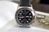 Stainless steel chronograph luxury wristwatch with black dial and leather strap on open book