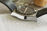 Luxury chronograph watch with black leather strap and polished case on an open book