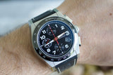 Luxury chronograph watch with black dial, white numerals, and black leather strap on wrist