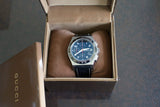 Luxury chronograph watch with black dial and leather strap displayed in an open box