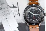 Vintage Heuer Bund SG 1550 flyback chronograph with black dial and leather strap on aviation photo background