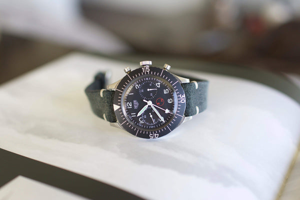 Vintage Heuer Bund chronograph with black dial and leather strap on display