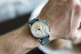 Vintage chronograph watch with cream dial and blue suede strap on wrist