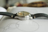 Vintage Swiss-made wristwatch with a leather strap on an open book, side profile view