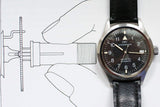 IWC Mark XII men's automatic pilot watch with black leather strap on technical drawing background