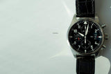 Luxury chronograph watch with black leather strap and black dial on light background