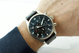 Swiss chronograph pilot watch with black leather strap on wrist, luxury pre-owned timepiece
