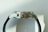 Side view of stainless steel chronograph watch case with crown and pushers, black strap