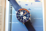 Blue and orange luxury chronograph dive watch with rubber strap on ocean depth chart background