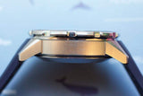 Side view of a luxury Swiss-made chronograph watch with brushed metal case and black strap