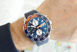 Blue and orange chronograph diver watch with three subdials on wrist, luxury Swiss-made design