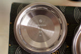 Stainless steel watch case back with engravings, shown close up on dark patterned background