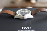 Luxury chronograph watch with brown leather strap and black dial on display box.