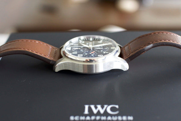Luxury chronograph watch with brown leather strap and black dial on display box.