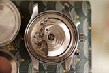 Close-up of luxury Swiss watch open caseback showing mechanical movement and rotor
