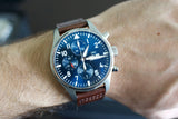 Luxury chronograph watch with blue dial and brown leather strap on wrist