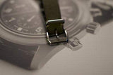 Close-up of a luxury chronograph watch buckle on a blurred watch face background