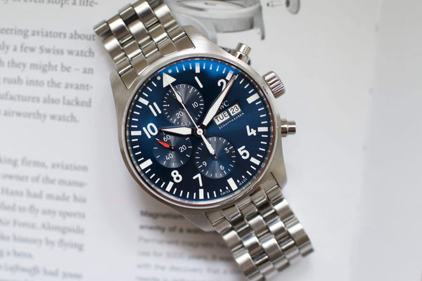 Blue dial chronograph pilot watch with stainless steel bracelet on open book background