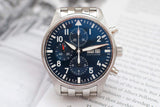 Stainless steel chronograph watch with blue dial and day-date display on open book background