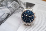 Stainless steel chronograph watch with blue dial and metal bracelet on open book