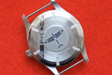 Rear case back of a Spitfire International Watch Co. watch on a red background
