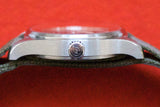 Side view of a luxury Swiss watch case and crown on a red background