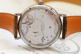 Close-up of luxury Swiss watch case back showing mechanical movement and brown leather strap
