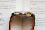 Side view of a luxury Swiss watch with a leather strap and polished crown