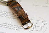 Close-up of luxury watch brown alligator leather strap with polished clasp on watch schematic