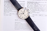 Close-up of a vintage IWC Chronograph Automatic wristwatch over a technical description page.
