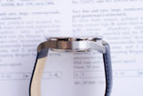 Side view of a luxury Swiss-made wristwatch with a blue leather strap on a document.