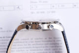 Close-up side view of a luxury Swiss watch with a leather strap and silver case